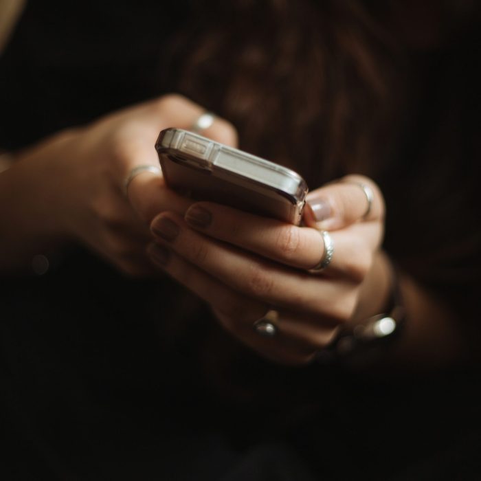Lady with a dark sweater holding a phone in her hand